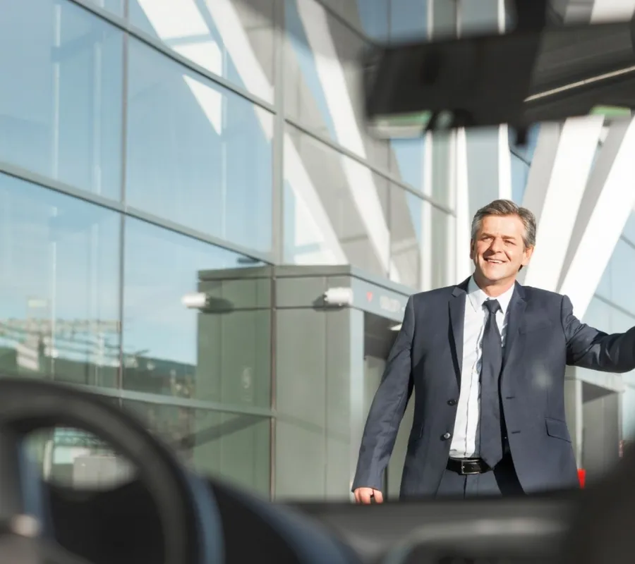 Airport transfer to and from Schiphol Smiling business traveller waving down his pre-booked airport taxi outside the terminal
