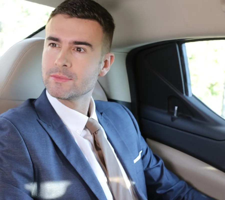 VIP and executive chauffeur service Business traveller in a blue suit relaxing in the back seat of a chauffeur-driven executive car